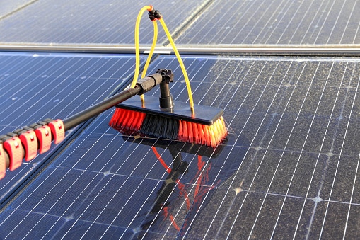Reinigung von Solarpanelen mit Wasser und Besen